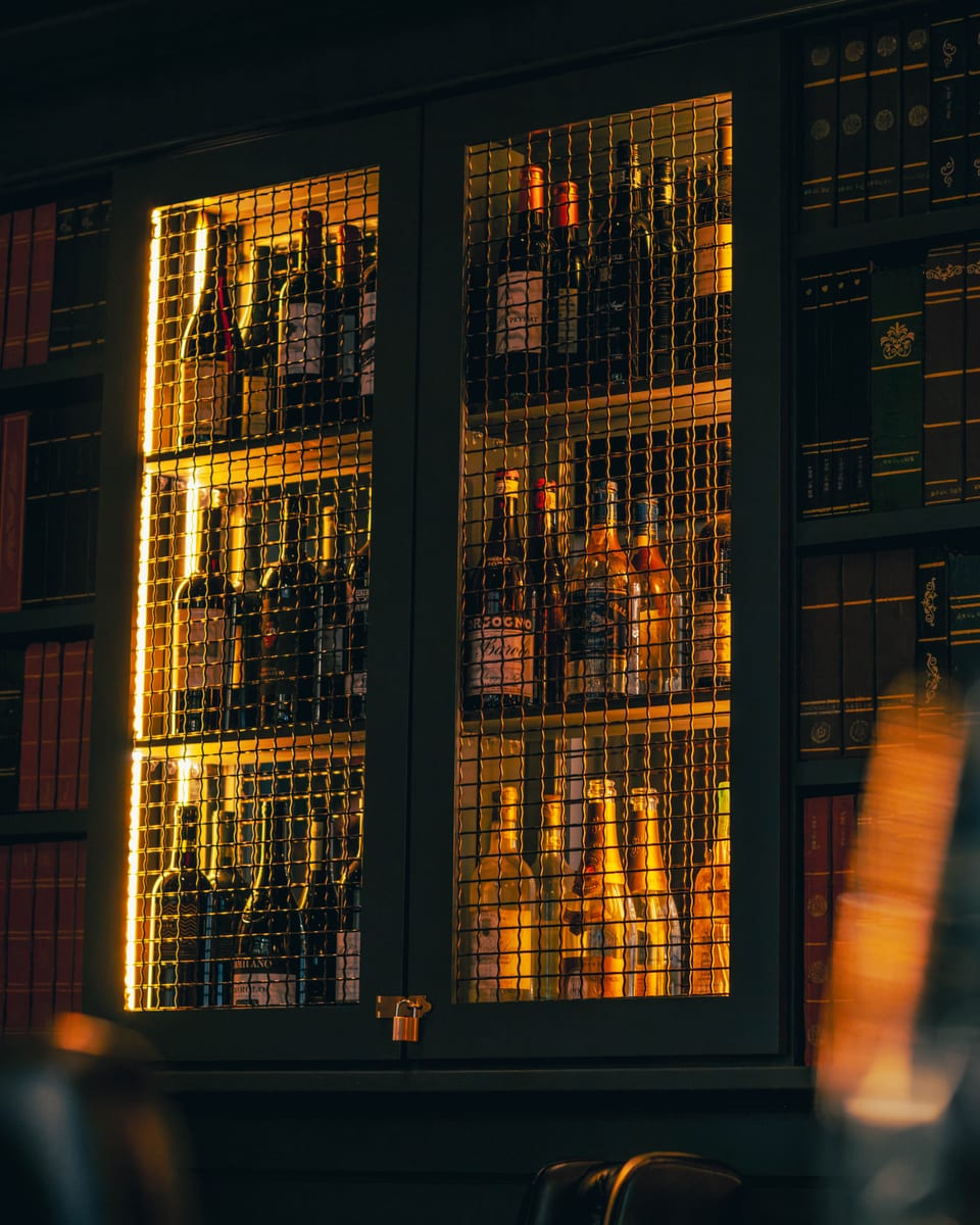 Backlit cabinets of wine and spirit bottles set into the library wall at Enology