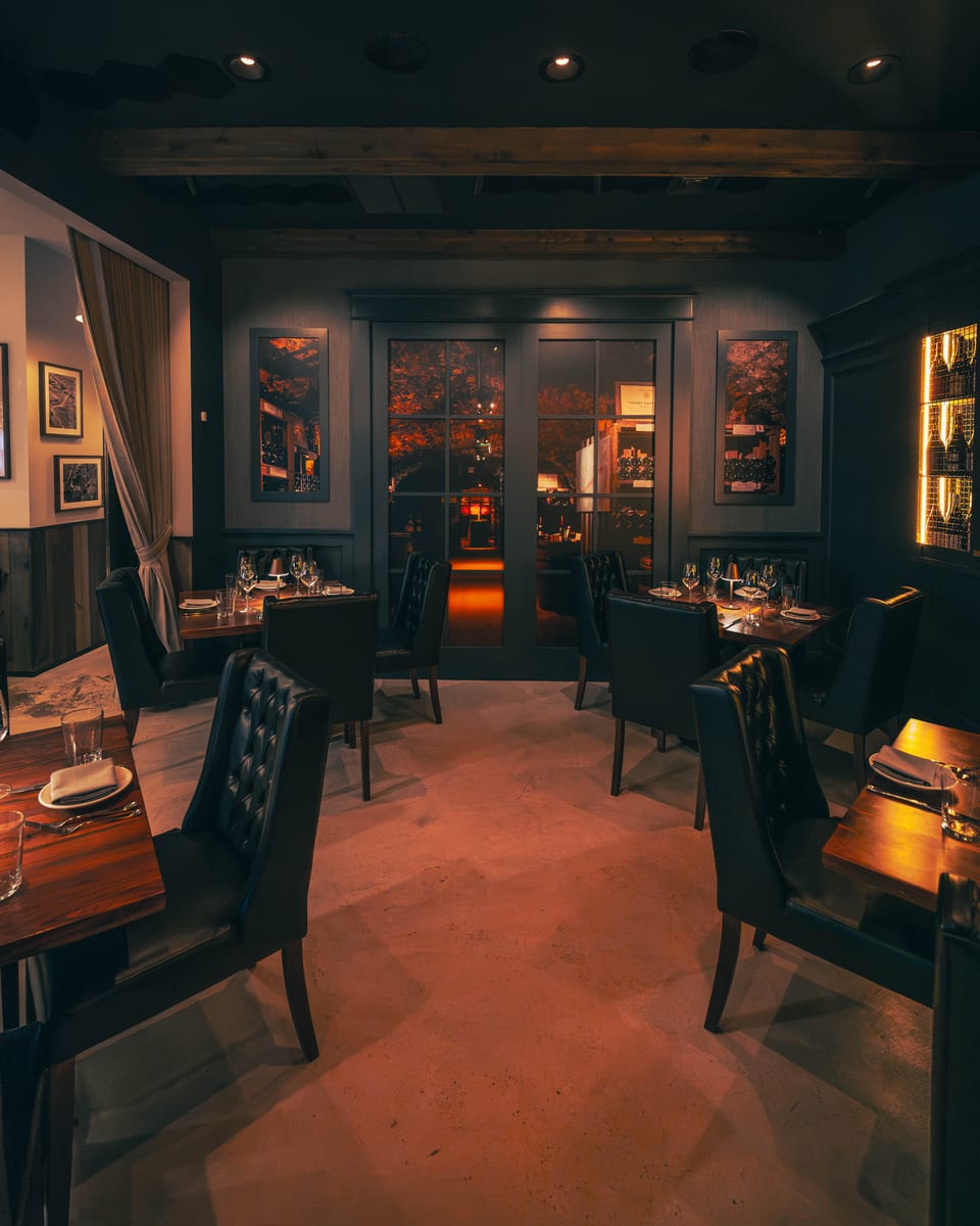 Glass doors at the back of the dining room opening onto the stone wine cellar