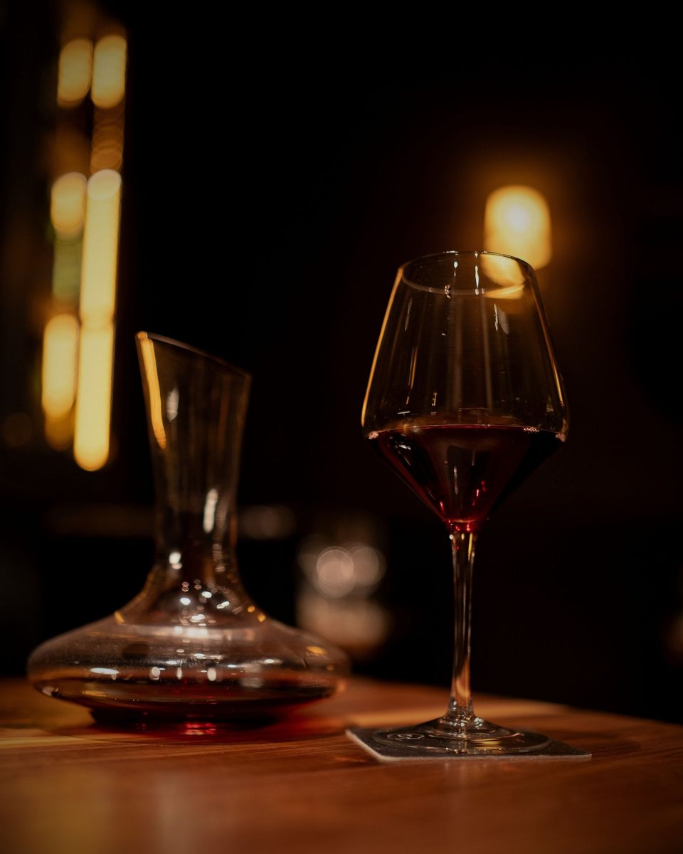 A decanter of red wine glowing in the warm light at Enology Wine Bar & Bistro