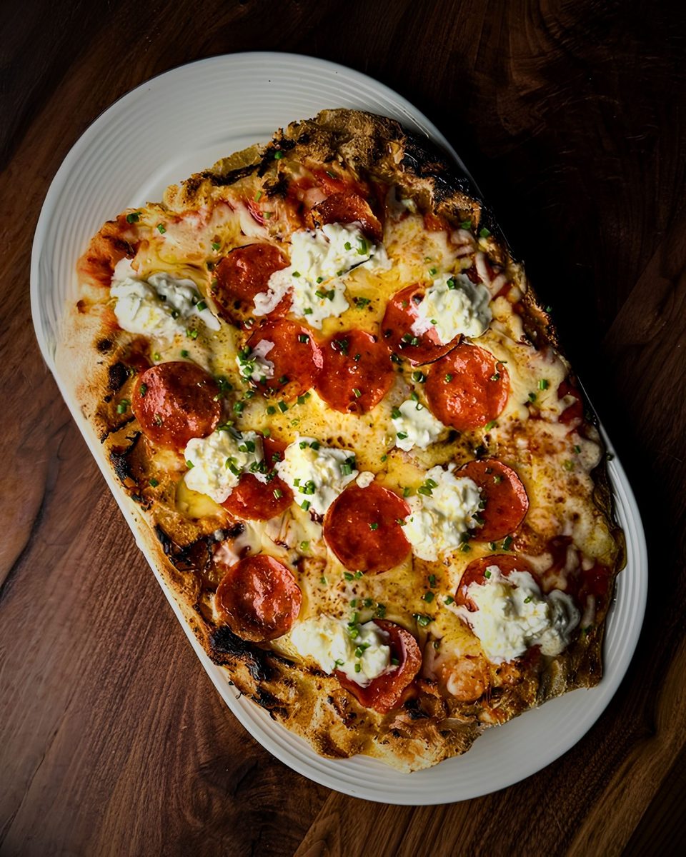A flatbread topped with pepperoni, ricotta, and chives