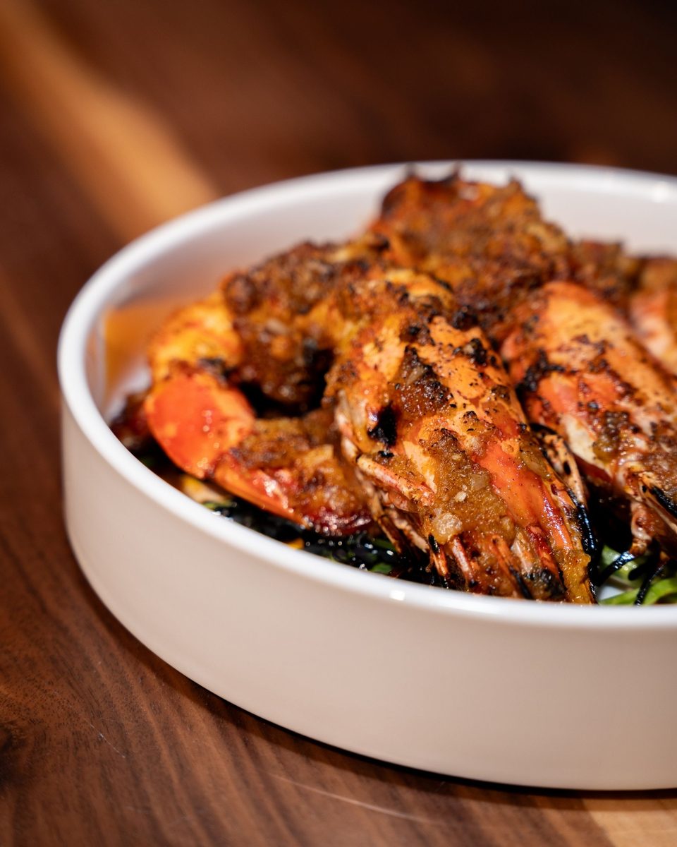 Char-grilled head-on shrimp with a spiced crust, served in a white bowl