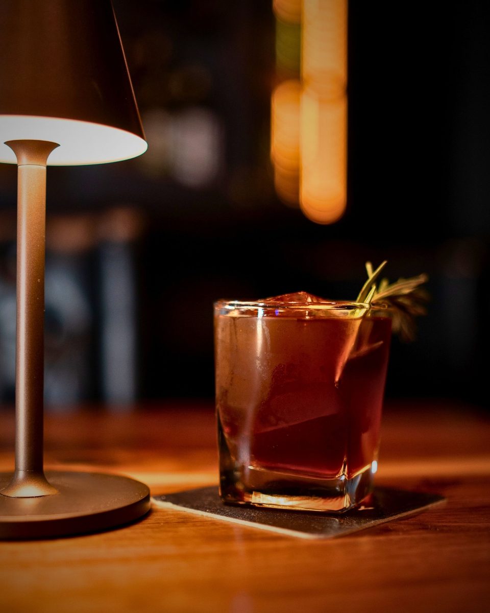 A spirit-forward cocktail over ice, garnished with rosemary
