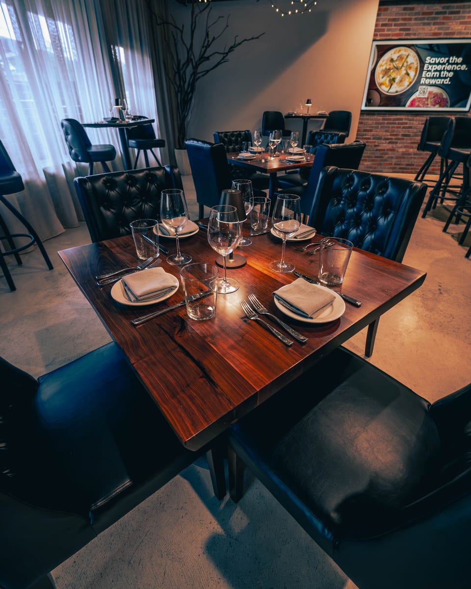 Walnut tables set beside the front windows of the Enology dining room