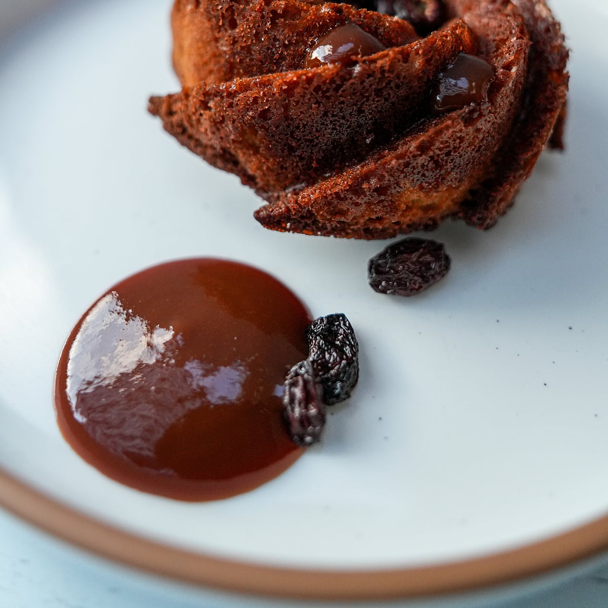 A rum bundt cake with caramel and raisins on a white plate