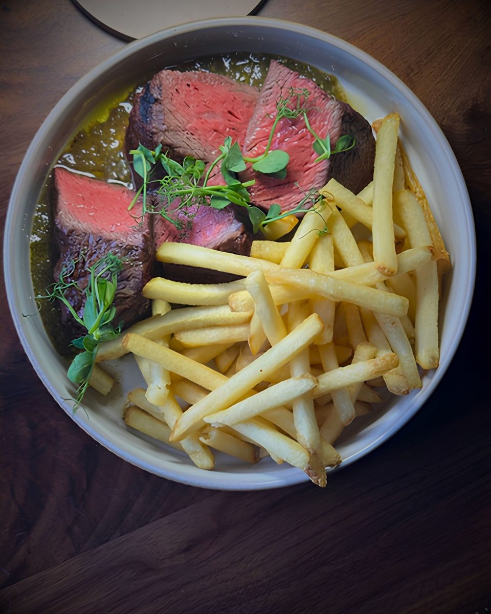 Steak frites, sliced rare with golden fries, from above