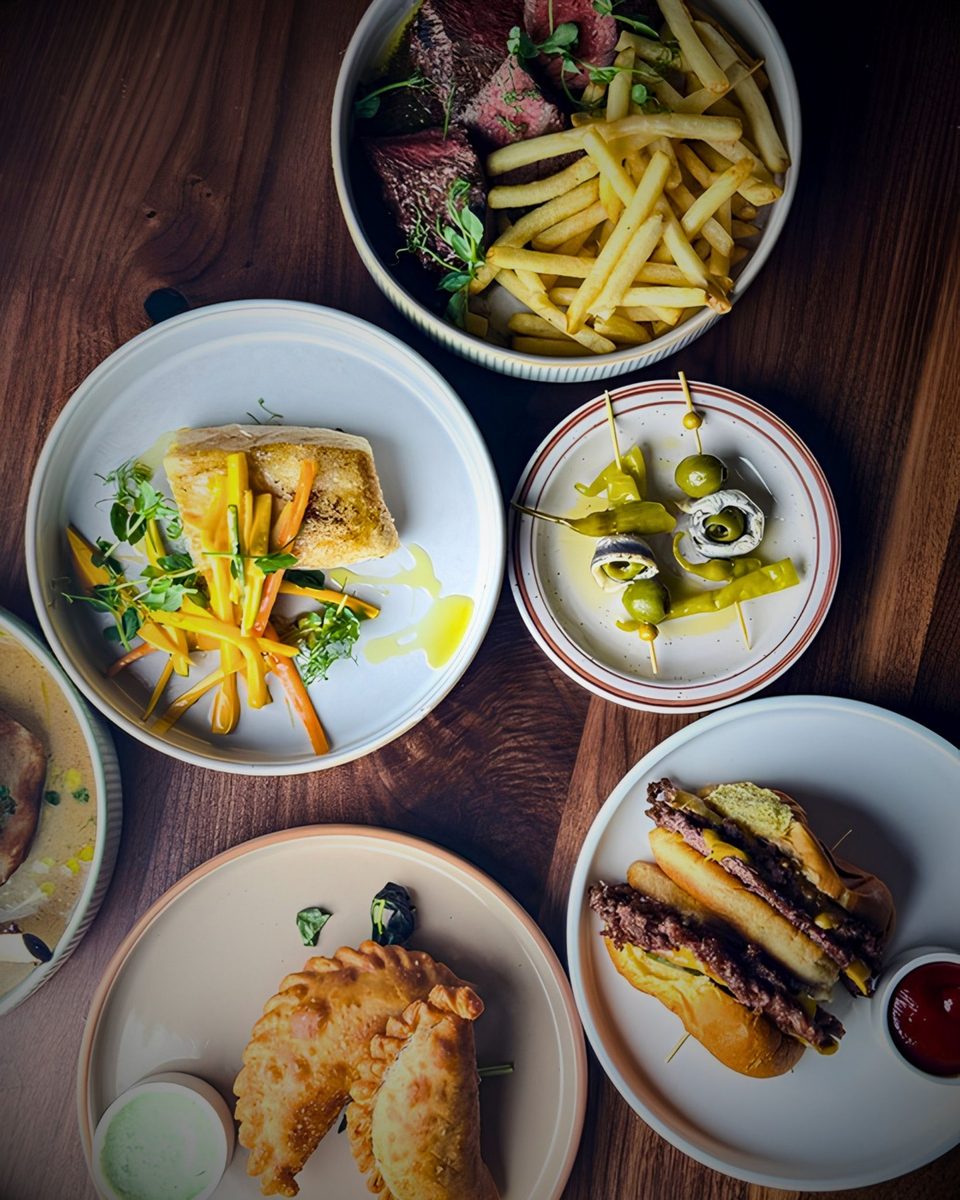 An overhead view of a full table of small plates and glasses at Enology Wine Bar and Bistro