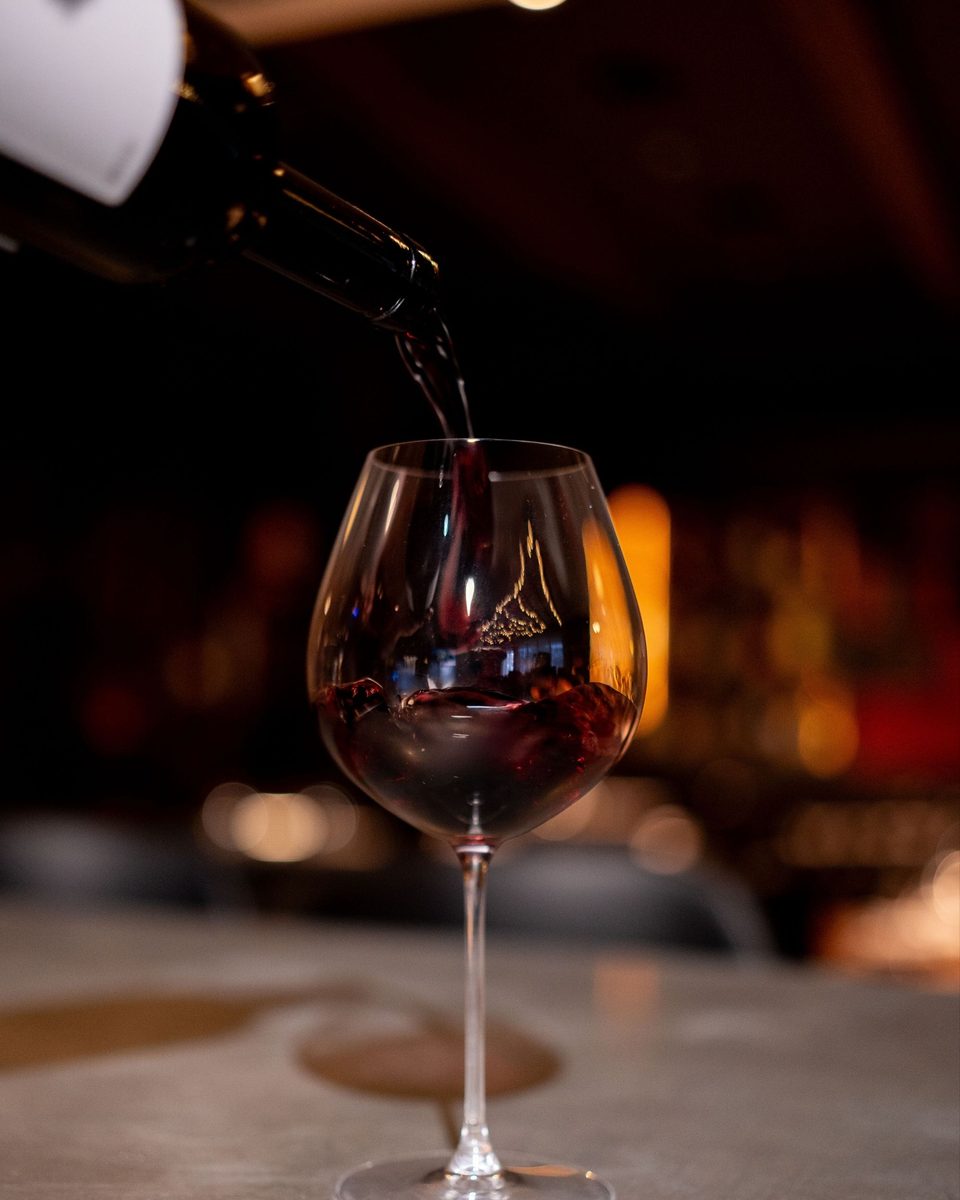 A glass of wine being poured at the bar at Enology Wine Bar & Bistro
