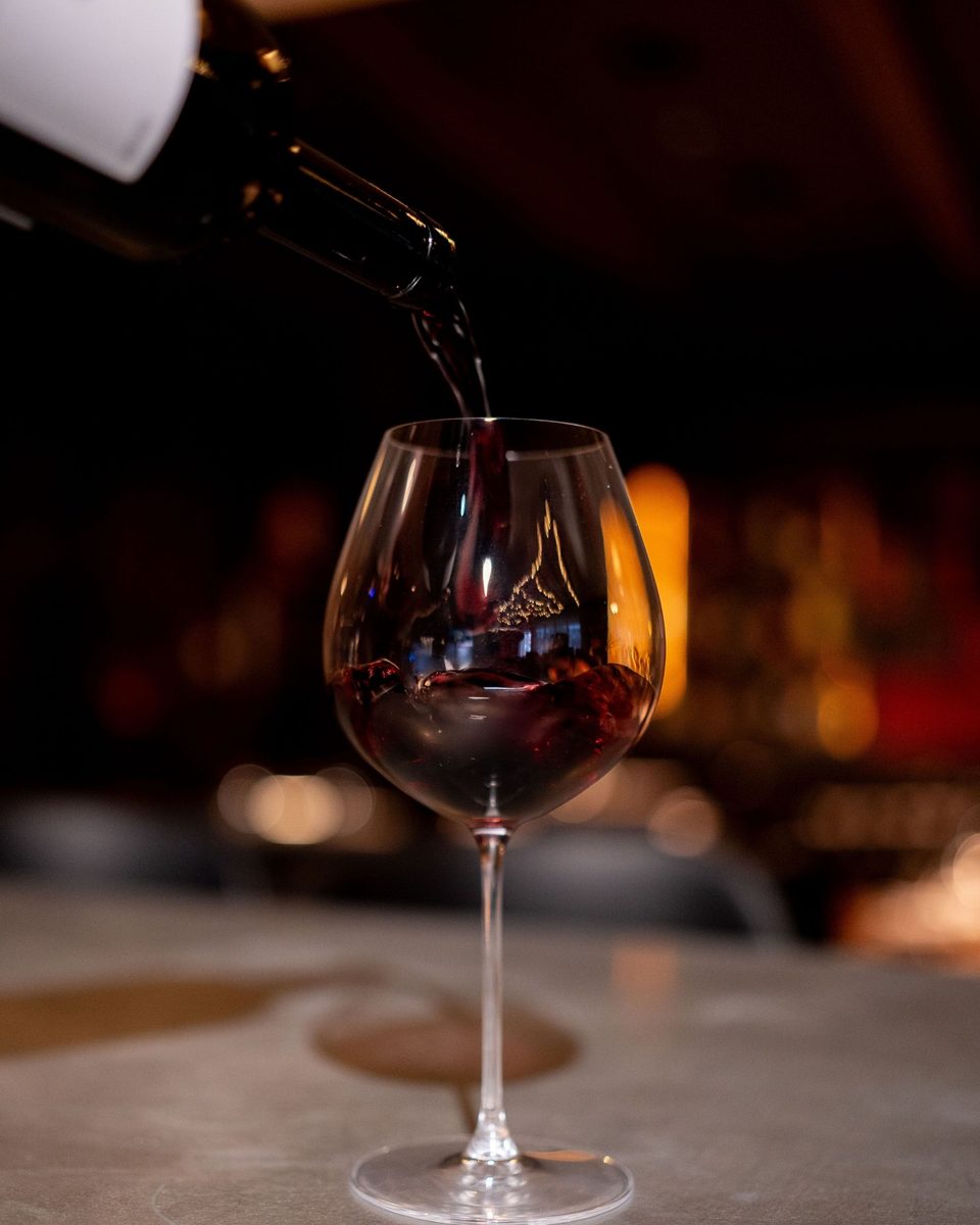A glass of red wine poured tableside at Enology